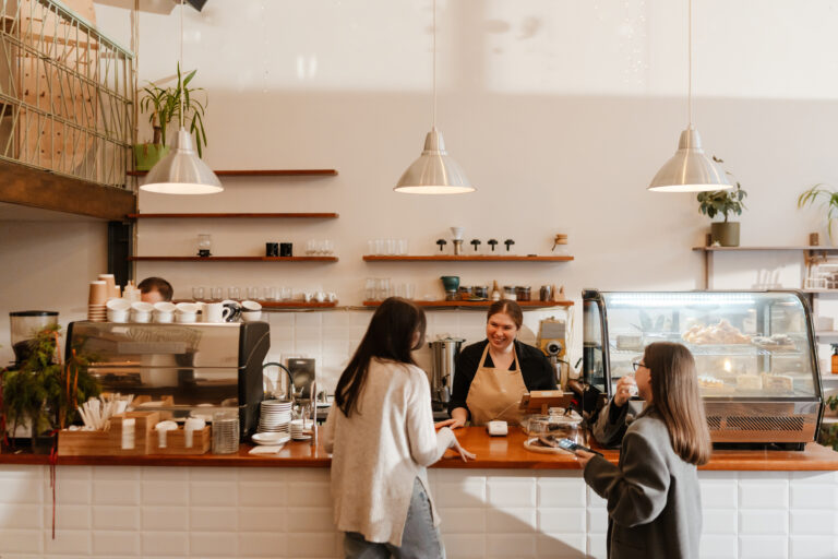 Café owner serving customers at the counter, a growing business that benefits from instant payouts to access card payment funds the same day