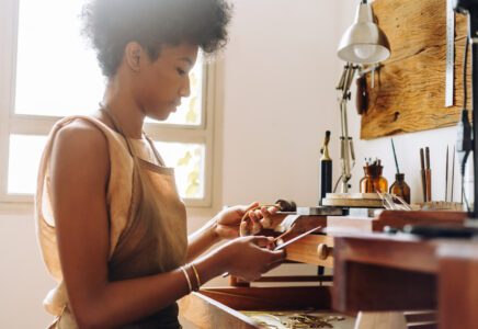 Independent jewelry maker at her studio workbench, a growing business owner managing her own payment processing costs