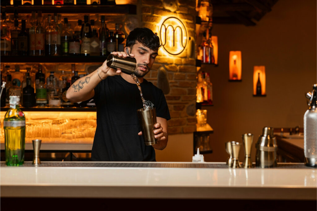 Bartender preparing a cocktail at a small business bar, where credit card processing fees apply to every transaction