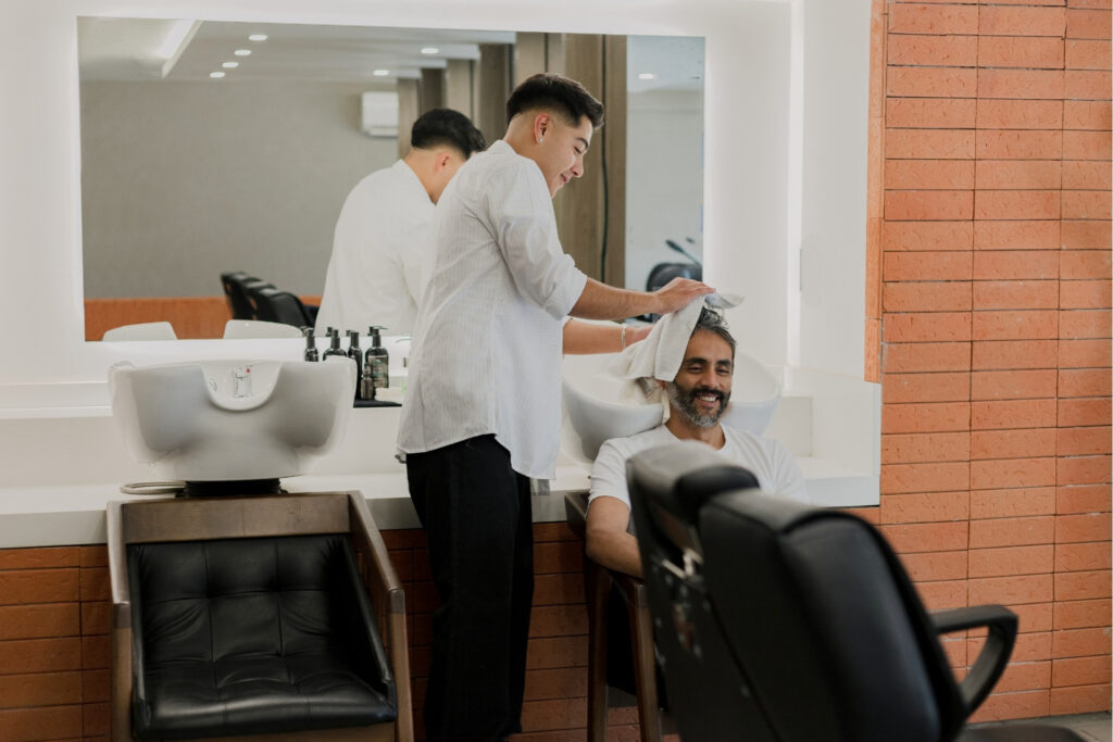 Hair stylist washing a client's hair at a salon, a personal care business that relies on instant payouts to manage cash flow between card settlements