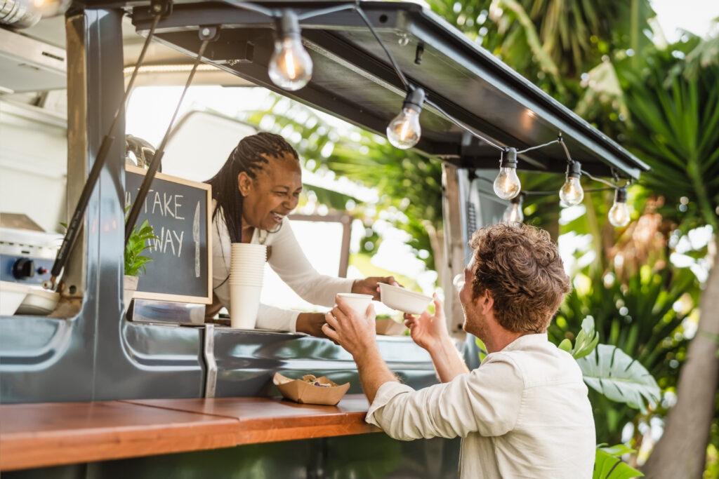 Food truck owner handing an order to a customer, a mobile business that uses instant payouts to close the gap between card sales and available cash