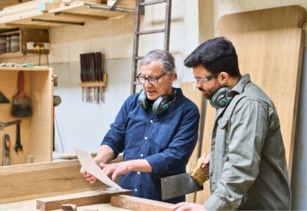 Two carpenters reviewing a project in their workshop, a service business that can use payment links to speed up collections and reduce unpaid invoices
