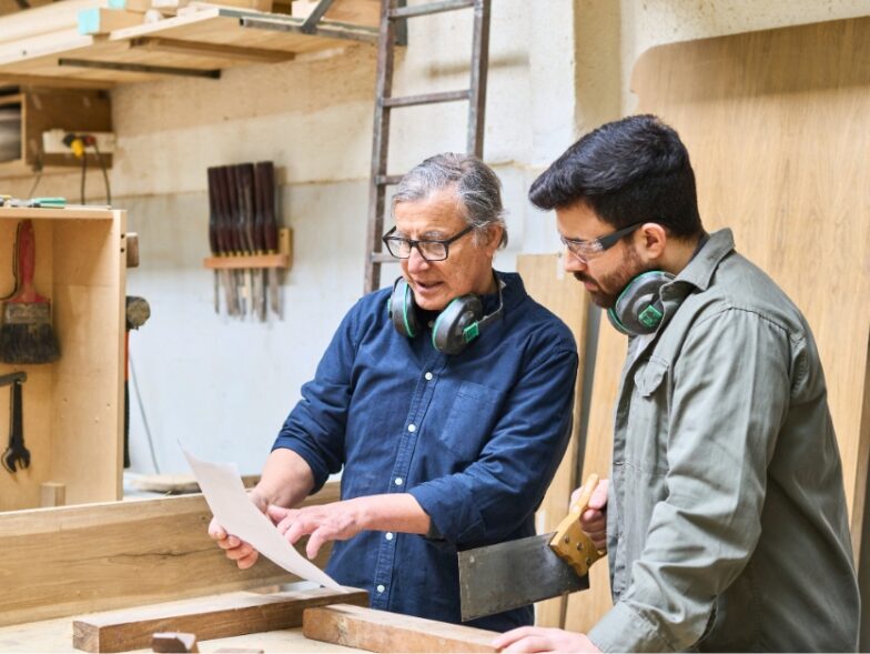 Two carpenters reviewing a project in their workshop, a service business that can use payment links to speed up collections and reduce unpaid invoices