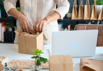 Small business owner packing a customer order at her desk, fulfilling online purchases to stay competitive during Prime Day