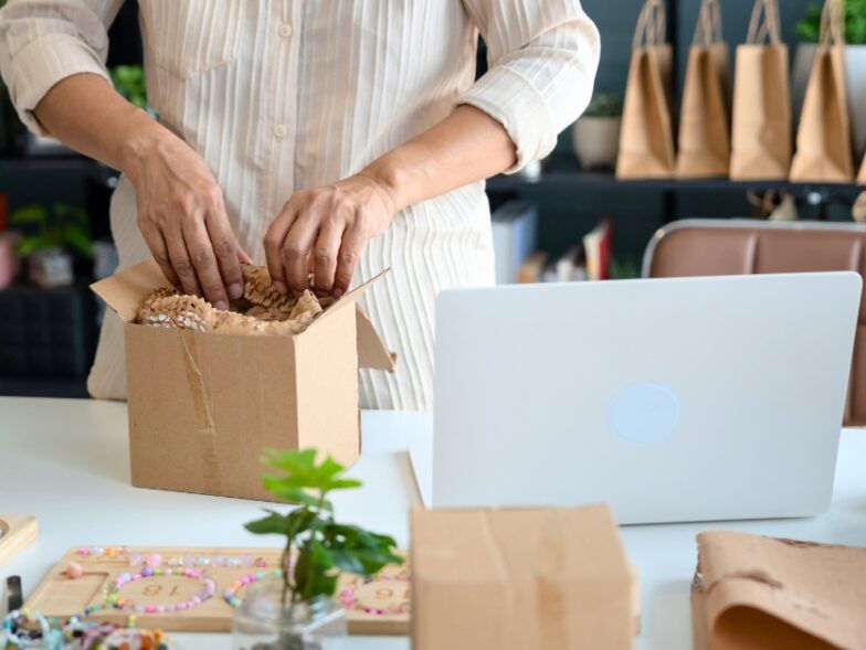 Small business owner packing a customer order at her desk, fulfilling online purchases to stay competitive during Prime Day