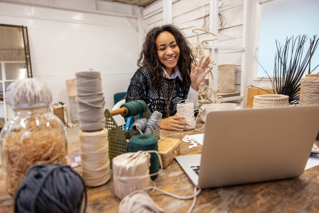 Small business owner gets ready for a live class after checking her sales and working capital on a laptop in her workshop, surrounded by her tools.