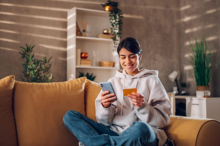 A smiling woman saves her credit card details on her smartphone to shop securely online.