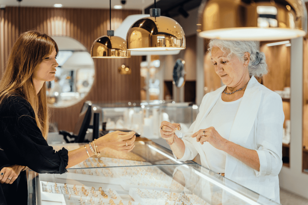 A jewelry store owner shows rings to a customer at the counter, where every card payment depends on secure processing.