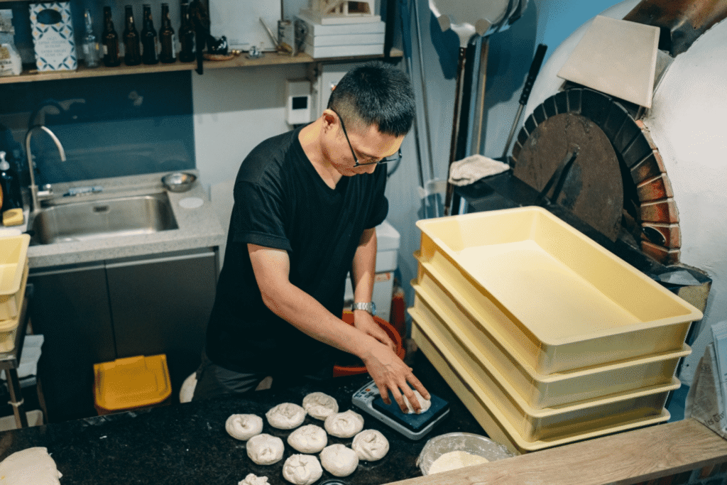 Small business owner weighs dough portions on a scale in his bakery kitchen — daily operations that a customer chargeback dispute can disrupt.