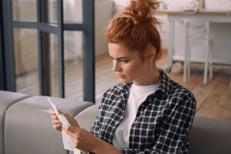 Woman frowning at a receipt, illustrating how an unrecognized charge can lead to a friendly fraud dispute