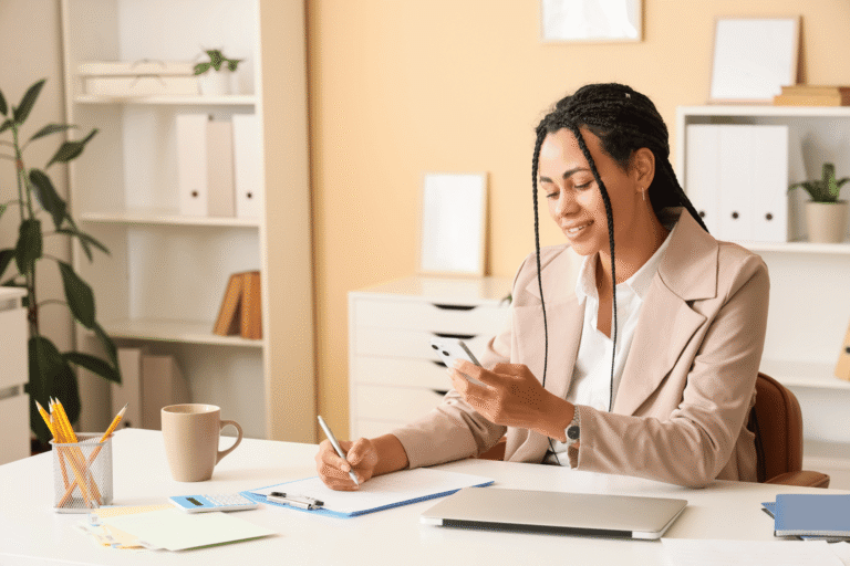 Small business owner sending a payment link from her smartphone at her office desk